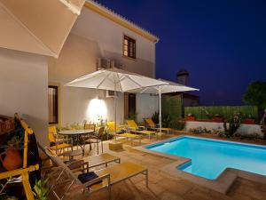 a swimming pool with chairs and a table and umbrellas at Betica Hotel Rural in Pias