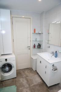 a white bathroom with a washing machine and a sink at Cozy Flat near Metro with Balcony in Tbilisi City