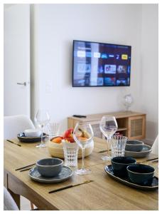 ein Holztisch mit Tellern und Weingläsern darauf in der Unterkunft Paisible 3 pièces, proche de Paris avec parking in Romainville