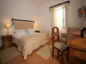 a bedroom with a bed and a chair and a window at Betica Hotel Rural in Pias