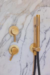 two gold showerheads and a comb on a marble counter at Hotel Belvedere in Forte dei Marmi