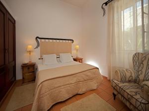 a bedroom with a large bed and a chair at Betica Hotel Rural in Pias