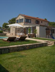 een huis met een parasol en stoelen en een zwembad bij Villa Royal with heated pool in Biograd na Moru