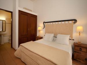 a bedroom with a large bed with white sheets and pillows at Betica Hotel Rural in Pias