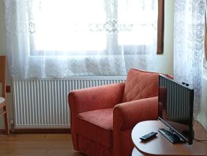 a living room with a red chair and a computer on a table at Къща за гости ЧЕРИ in Tryavna