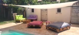 Un patio con dos camas y sillas y una piscina. en Gite LA DEPENDANCE, en Le Cailar