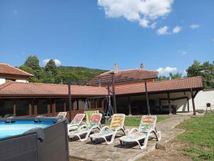 a group of lawn chairs sitting next to a pool at Къща за гости ЧЕРИ in Tryavna