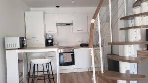 a small kitchen with white cabinets and a staircase at Le Nid Daudèce in Le Châtelet-sur-Sormonne