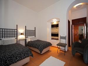a bedroom with two beds and a chair and a table at Betica Hotel Rural in Pias