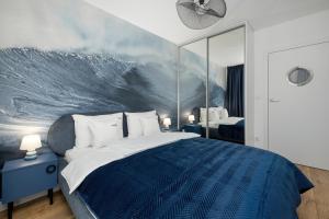 een slaapkamer met een blauw bed met een golfmuurschildering bij Apartamenty Baltic Marina in Międzywodzie