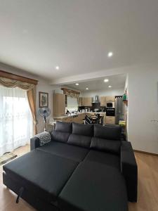 a living room with a black couch and a kitchen at Alojamento Luna in Porto Judeu