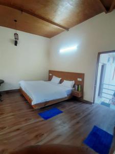 a bedroom with a white bed and a wooden floor at shri Chandra homestay kainchidham in Nainital