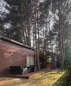 a log cabin with a porch with couches and trees at Domek z balią in Zwierzyniec