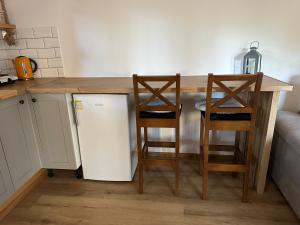 a kitchen with a counter with two chairs and a refrigerator at Domek z balią in Zwierzyniec +4 photos