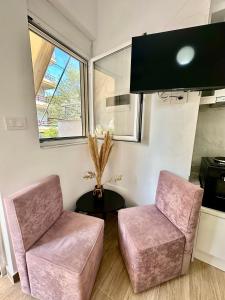 two pink chairs and a table in a room at Adela's Saranda Central Apartment in Sarandë