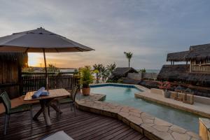 Una terraza con una mesa y una sombrilla y una piscina. en Dayo Hotel, en Flecheiras