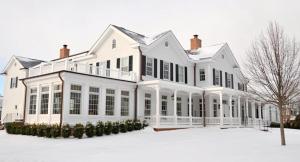 a large white house with snow on the ground at The Quogue Club in Quogue