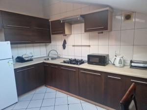a kitchen with brown cabinets and a sink and a microwave at Apartament Pracowniczy in Pogórze