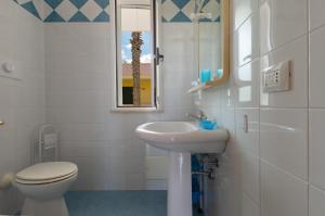 ein Badezimmer mit Waschbecken, Toilette und Spiegel in der Unterkunft Villino Raffy by BarbarHouse in Torre dell'Orso