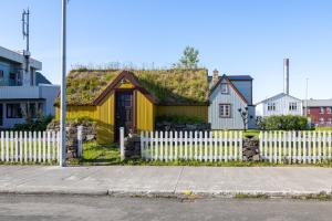 a yellow house with a grass roof with a white fence at The Sigló House in Siglufjörður