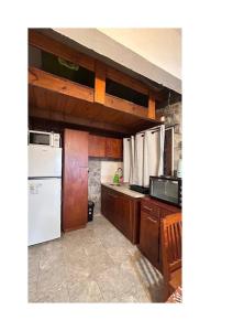 a kitchen with wooden cabinets and a white refrigerator at Relax by the sea in Piriápolis +24 photos