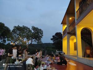 a group of people sitting at tables outside a building at Tổ Homestay in Tân Phú