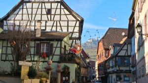 a city street with buildings and a mountain in the background at La Tour Enchantée in Ribeauvillé