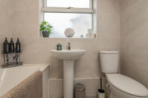 a bathroom with a sink and a toilet and a window at Spacious 5 Bed Close to Elland Road, First Direct Arena & Headingley Stadium in Roundhay +8 photos