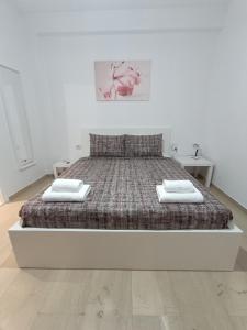 ein weißes Schlafzimmer mit einem Bett, auf dem zwei Handtücher liegen in der Unterkunft T.G. Corfu Studios in Korfu-Stadt