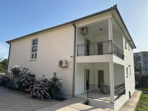 a white building with a balcony and some flowers at Apartmani Aki 6 in Sutomore