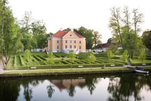 a large house with a river in front of it at Palmse Distillery Guesthouse - Self Check-in in Palmse