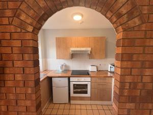 a kitchen with a brick wall and an archway at Causeway Coast Apartment in Ballycastle