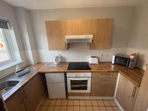 a small kitchen with wooden cabinets and a microwave at Causeway Coast Apartment in Ballycastle