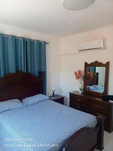 Schlafzimmer mit einem Bett mit blauen Vorhängen und einem Spiegel in der Unterkunft Cómodo y cerca de la playa in Punta Cana