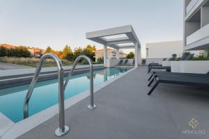 a swimming pool with benches next to a building at Nemausa Luxury Living in Kallithea Halkidikis