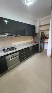 a kitchen with black cabinets and a stainless steel refrigerator at Appartement moderne équipé, situé au centre de Oujda in Oujda +6 photos