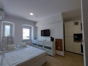 a white bedroom with a bed and a television at Agostini Residence - SELF CHECK-IN ONLY in Rijeka