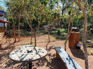 einen Park mit einer Bank, einem Tisch und Bäumen in der Unterkunft Camping dos oliveira in Jaboticatubas