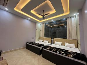 two beds in a room with a ceiling at Hotel S K in Naimishāranya