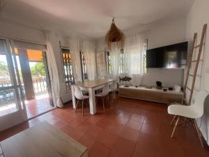 a dining room with a table and chairs and a tv at PINO BEACH in Punta Umbría