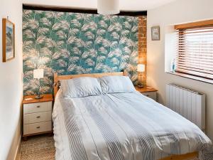 une chambre avec un lit avec un papier peint tropical dans l'établissement Trailor Cottage, à Weybourne