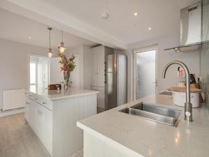 a white kitchen with a sink and a refrigerator at Little Dab in Brancaster +12 photos