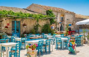 a group of tables and chairs in front of a building at La casa della Tonnara, Marzamemi in Marzamemi