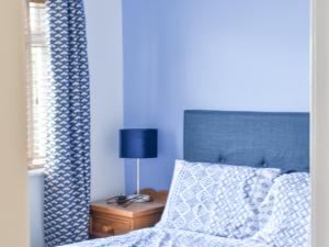 une chambre bleue avec un lit et une lampe sur une table de chevet dans l'établissement Cranleigh, à Pakefield 4 autres photos