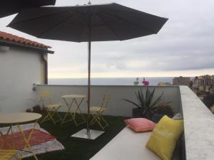 a black umbrella on a balcony with chairs and tables at Joy19 B&B in Albissola Marina