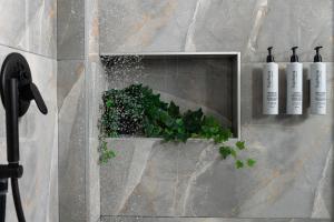 a wall with a niche with a plant and three bottles at Heaven Hotel Thessaloniki Airport in Néon Rýsion