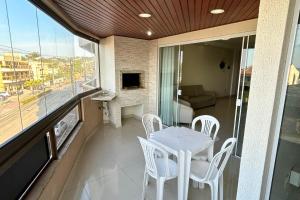 a balcony with a white table and chairs on it at Apartamento com vista mar e excelente localização in Bombinhas