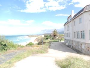 a building on the side of a road next to the beach at Hostal Acantilado in Villadaíde