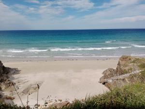 a sandy beach with the ocean in the background at Hostal Acantilado in Villadaíde +5 photos