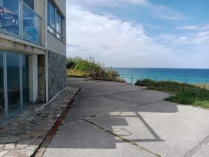 a sidewalk next to a building next to the ocean at Hostal Acantilado in Villadaíde